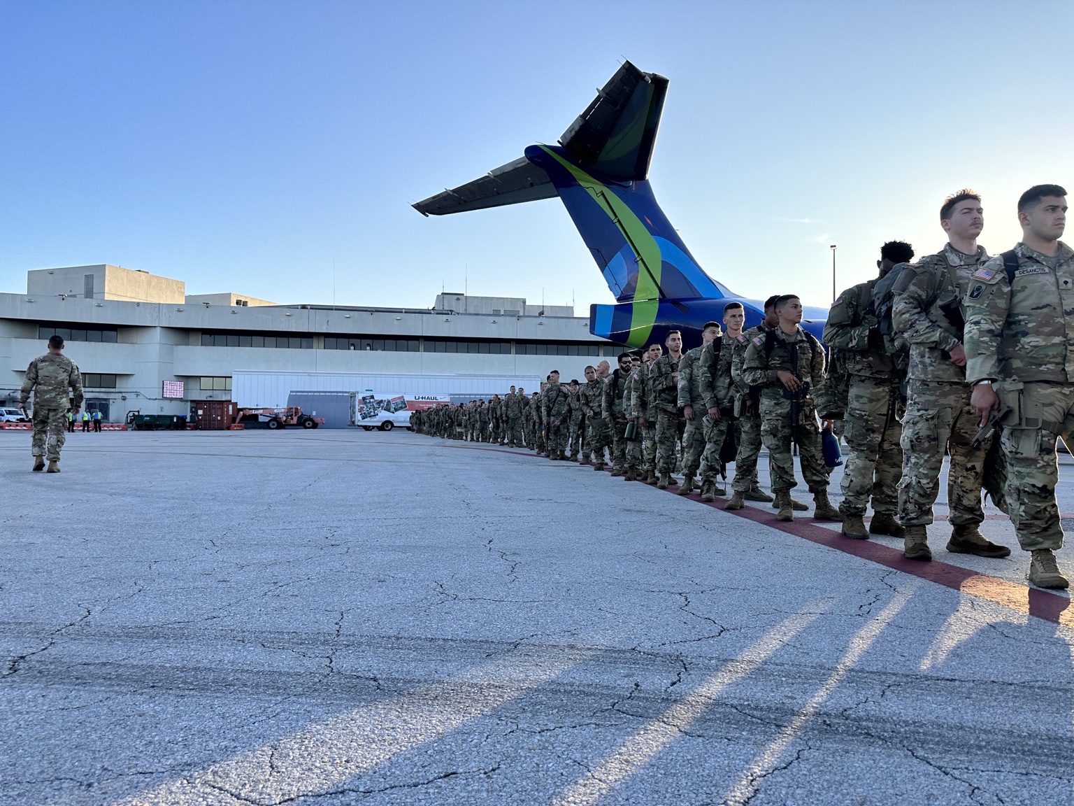 Personnel awaiting transportation alongside a passenger aircraft
